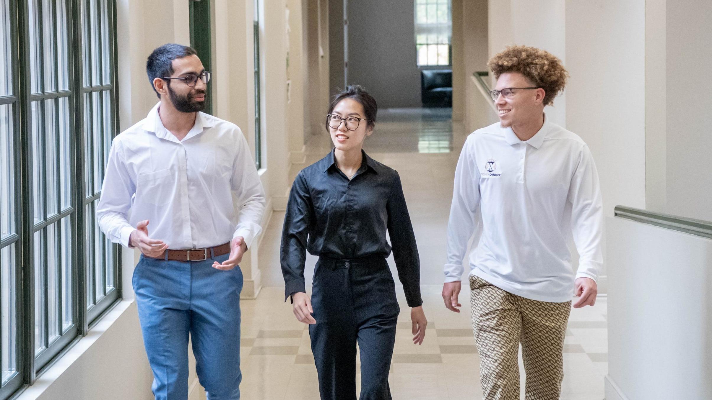 Three students walking and talking in the College of Business and Aviation lobby.